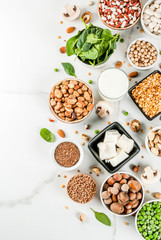 Healthy diet vegan food, veggie protein sources: Tofu, vegan milk, beans, lentils, nuts, soy milk, spinach and seeds. Top view on white table.