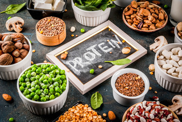Healthy diet vegan food, veggie protein sources: Tofu, vegan milk, beans, lentils, nuts, soy milk, spinach and seeds. Top view on white table.