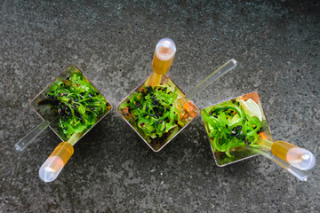 Three mini fresh salads with sauce on grey background. Selective focus.Top view