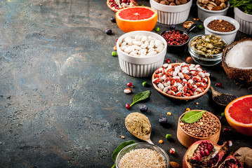 Set of organic healthy diet food, superfoods - beans, legumes, nuts, seeds, greens, fruit and vegetables. Dark blue background copy space top view