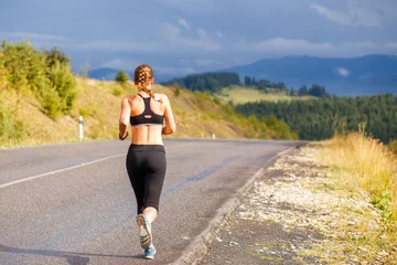 Afwasbaar Fotobehang Joggen Jonge sportieve vrouw joggen op bergweg. Running fitness meisje in sportkleding buiten afbeelding met kopie ruimte