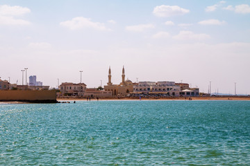 Fototapeta premium People are enjoying a sunny day on a beach in Ras Al Khaimah. Minaret in background, UAE