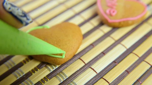 the woman decorates the confectioner and decorates the croquet with the glaze on the Valentine's Day. The inscription love on home cookies is handmade.