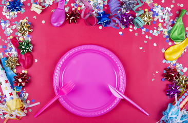 Celebratory red background with confetti and balloons, with children plate, fork and knife in the middle. Copyspace Mockup ..