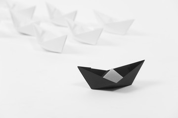 creative black paper ship among white. concept leadership different.