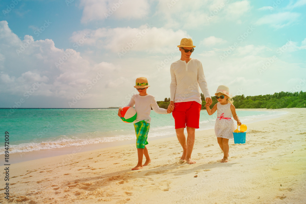 Wall mural father and two kids walking on beach