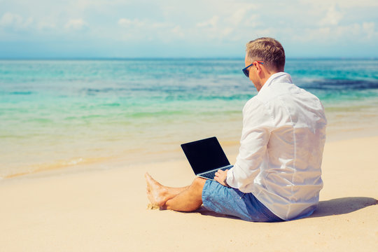 Young businessman using laptop computer on the beach