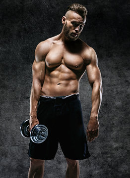 Athletic young man having a break. Photo of sporty muscular man with perfect body on dark background. Strength and motivation.