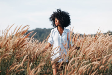 Fototapeta premium wesoły african american młoda kobieta na polu o zachodzie słońca
