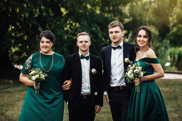 Newlywed couple, bridesmaids & groomsmen having fun outdoors