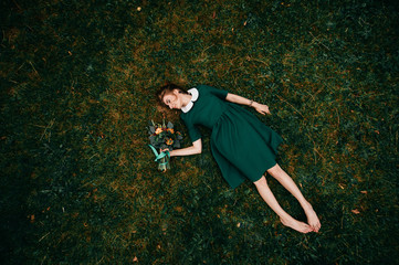 Young girl with red hairlying on ground. Portrait from above of cute teenager female relaxing on...