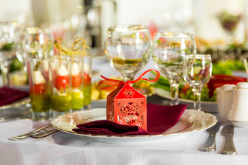 Banquet table, there is a red box with a gift on the plate.