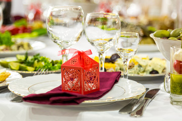 Banquet table, there is a red box with a gift on the plate.