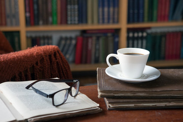 Sweet moments of relaxation with books and a cup of coffee. Vintage books, glasses, chair, library