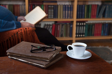 Sweet moments of relaxation with books and a cup of coffee. Vintage books, glasses, chair, library, man
