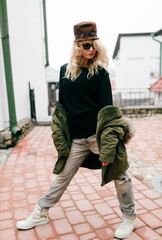 Fashionable young girl model in trendy famous italian jeans and white old fashioned expensive sneakers posing for camera. European beautiful woman stylish look. Well dressed woman. Modern appearance.
