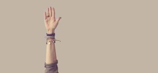 Woman arm up, palm open on grey background