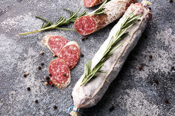 sliced salami and salami sausage on grey background