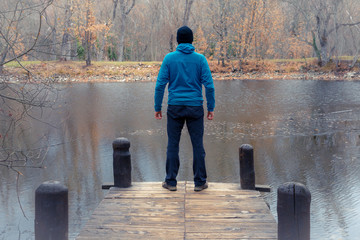 Unrecognizable mountaineer standing on mountain pier in the middle of the forest.