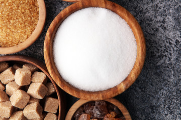 Various types of sugar, brown sugar and white on grey table