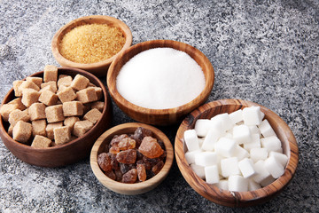 Various types of sugar, brown sugar and white on grey table