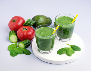 Fresh Tasty Spinach Cucumber Avocado Tomato Smoothie in Glasses Fresh Vgetables Detox Drink White Wooden Tray Gray Background Horizontal