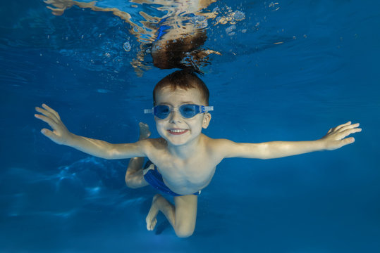4 years boy in swimming goggles play under water in the pool