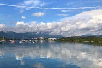 Mountain, blue sky, boats, yacht and sailboats on lake