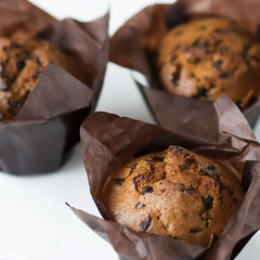 A chocolate muffins in brown paper on a white background.