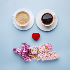 Pink hyacinth flowers, gift box and two cups of coffee on blue background.