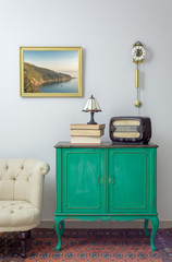 Interior shot of green vintage sideboard with old radio, stack of old books, and table lamp on...