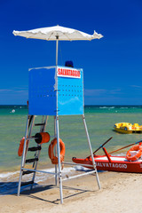 Lifeguard tower and a typical red catamaran in Italy. Summer day on the beach.