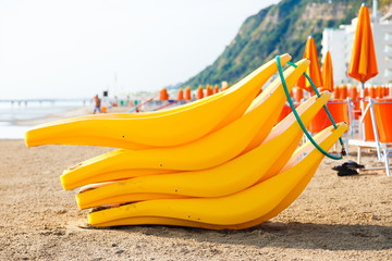 The banana boat on the empty beach with a lot of sunbeds and umbrellas on the background.