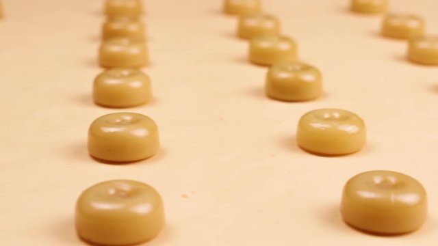 Sweet caramel candys on pastel yellow surface.