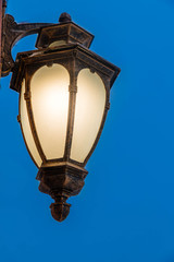 Fototapeta na wymiar Vintage lamp glowing in the evening against a dark blue sky.