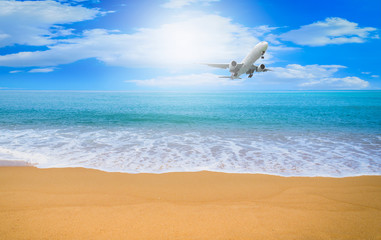 Plane flying on blue sky with cloud background over beach and tropical sea.