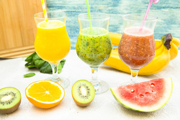Tropical Healthy Smoothie with fresh kiwi, banana, watermelon and spinach on white against a blue wooden wall, top view. Diet, Detox, Healthy Dessert Concept