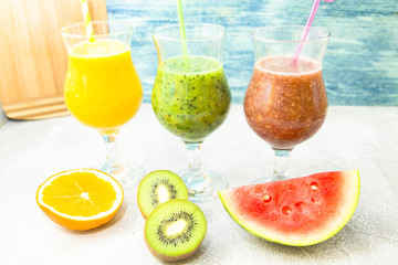 Tropical Healthy Smoothie with fresh kiwi, banana, watermelon and spinach on white against a blue wooden wall, top view. Diet, Detox, Healthy Dessert Concept