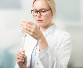 Junge hübsche Ärztin zieht Serum in Spritze auf