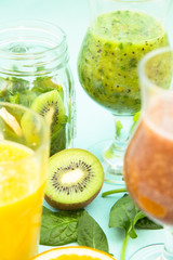 Preparing homemade tropical smoothie with kiwi, grapes, banana, orange, watermelon and spinach on a light blue background. Diet, Fitness, Dessert Concept