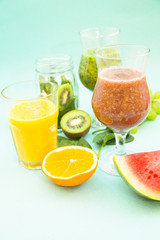 Preparing homemade tropical smoothie with kiwi, grapes, banana, orange, watermelon and spinach on a light blue background. Diet, Fitness, Dessert Concept