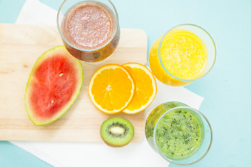 Tropical Smoothie Cocktail with fresh watermelon, orange, grapes and bananas. Light blue background, top viewHealthy food, Diet, Fitness, Dessert Concept