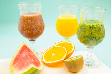 Tropical Smoothie Cocktail with fresh watermelon, orange, grapes and bananas. Light blue background, top viewHealthy food, Diet, Fitness, Dessert Concept