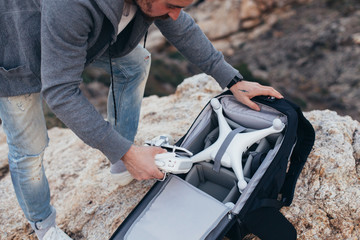 Obraz premium Urban adventurer or explorer, stock photographer unpacks backpack with photography equipment and drone. Ready to shoot aerial footage for sale or social media