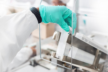 Hand placing labels into a label inserting machine in Pharmaceutical manufacturing process.