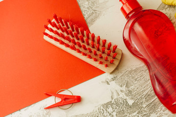 Set of red cleaning tools on a light concrete background: wooden clothes brush, clothes peg and...