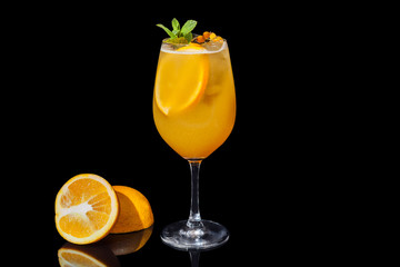 Alcoholic orange juice on a black background decorated with an orange slice and mint. Alcoholic orange juice on a black background.