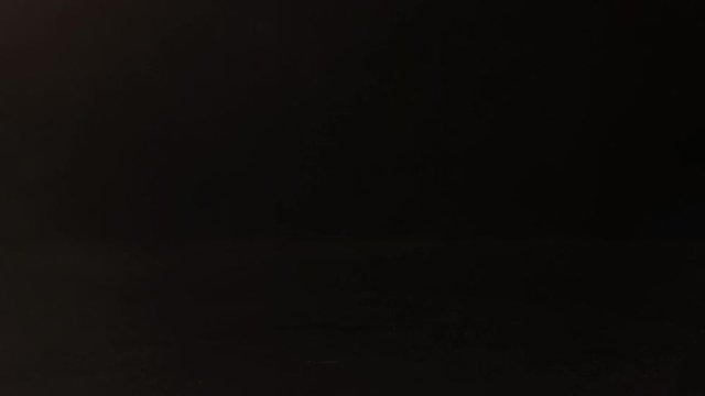 Glass of alcohol sliding across the bar counter. Hand picks up a drink on black background.