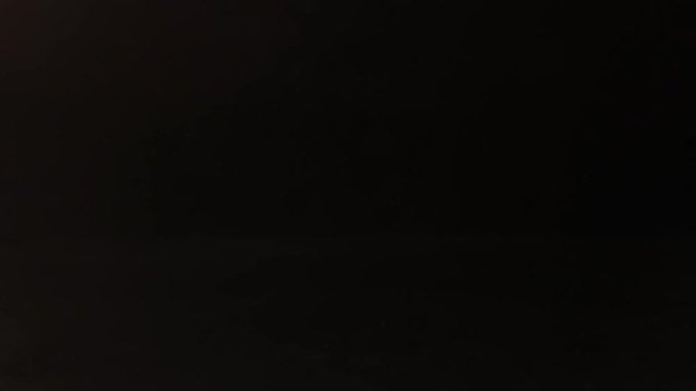 Glass of alcohol sliding across the bar counter. Hand picks up a drink on black background.