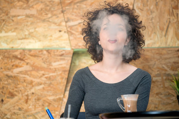Trendy hipster girl enjoying hookah at a modern coffee shop
